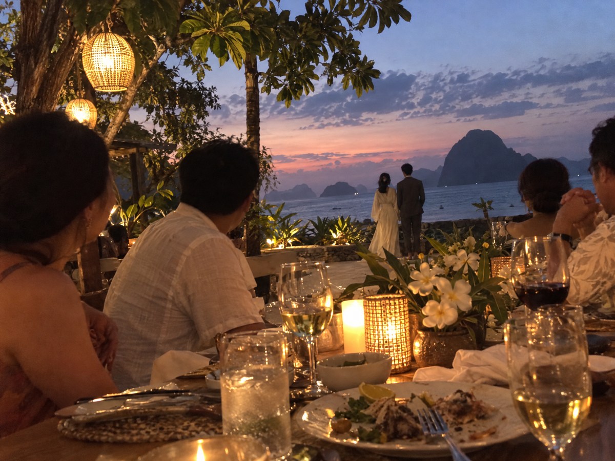 Hana and Kenji far off at the edge of the terrace, looking out at the last light.