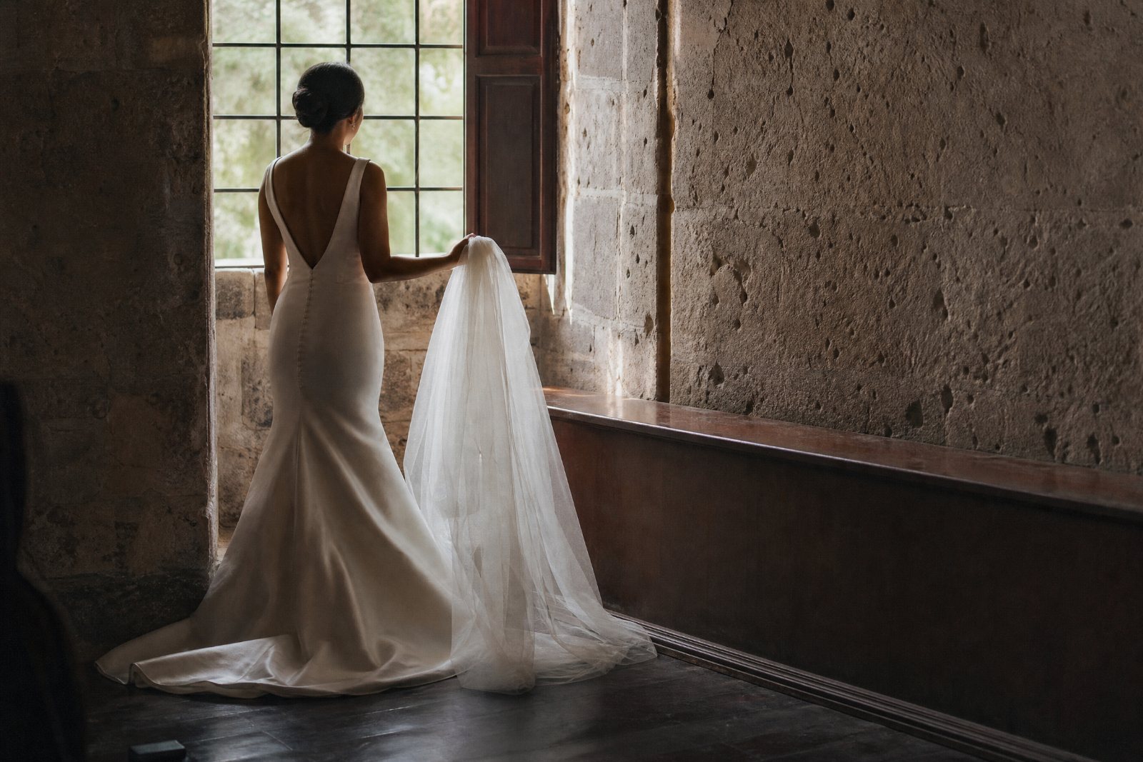 Andrea seen from behind at a window, veil not yet pinned.