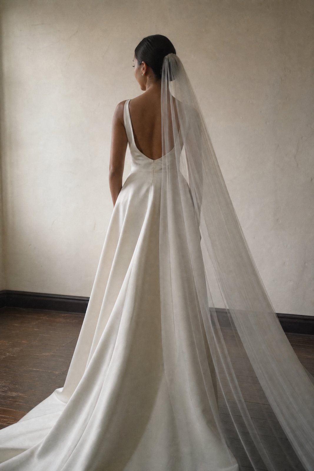 Andrea photographed from behind in her gown, veil falling the length of the floor.