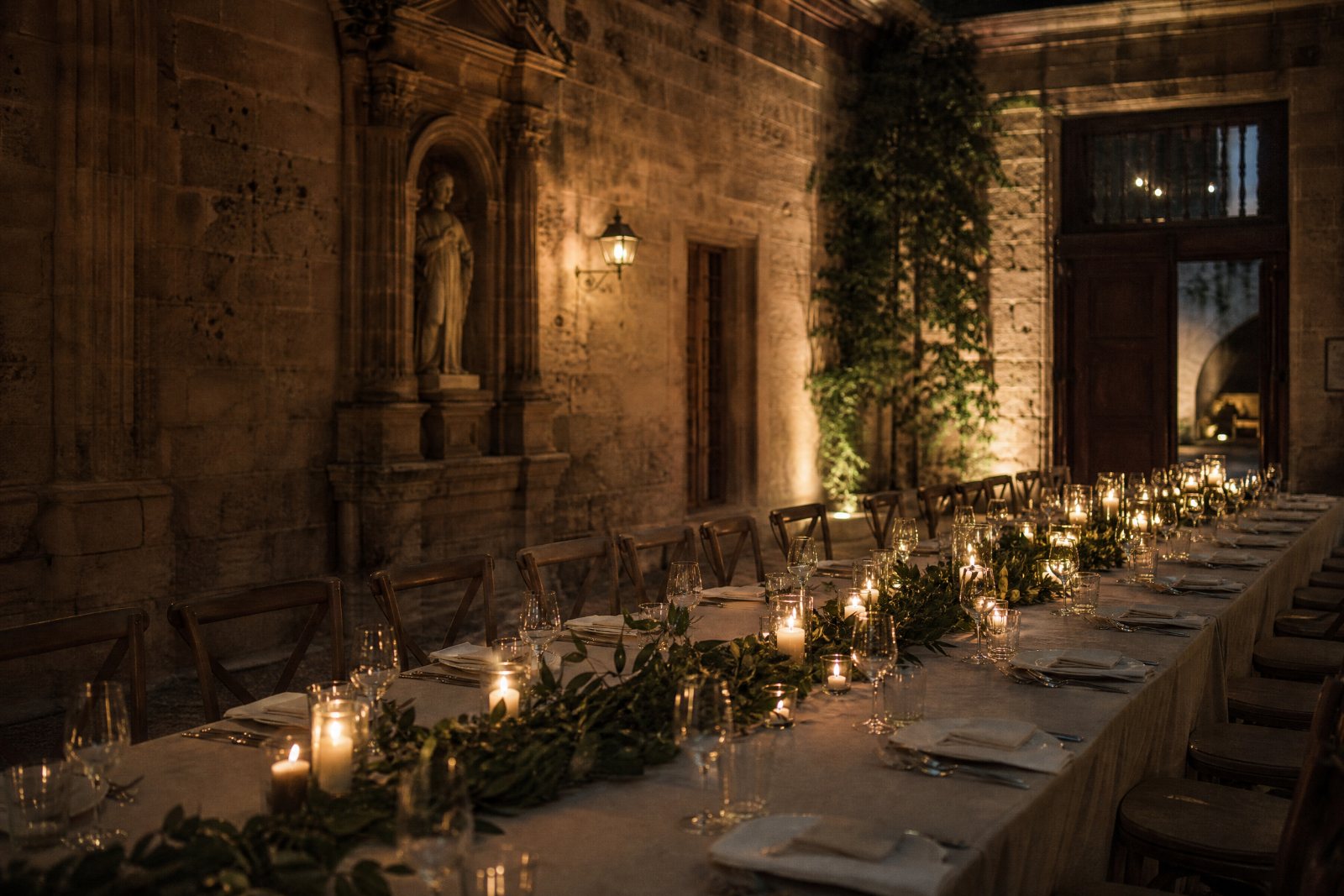A long reception table set for dinner in warm evening light.