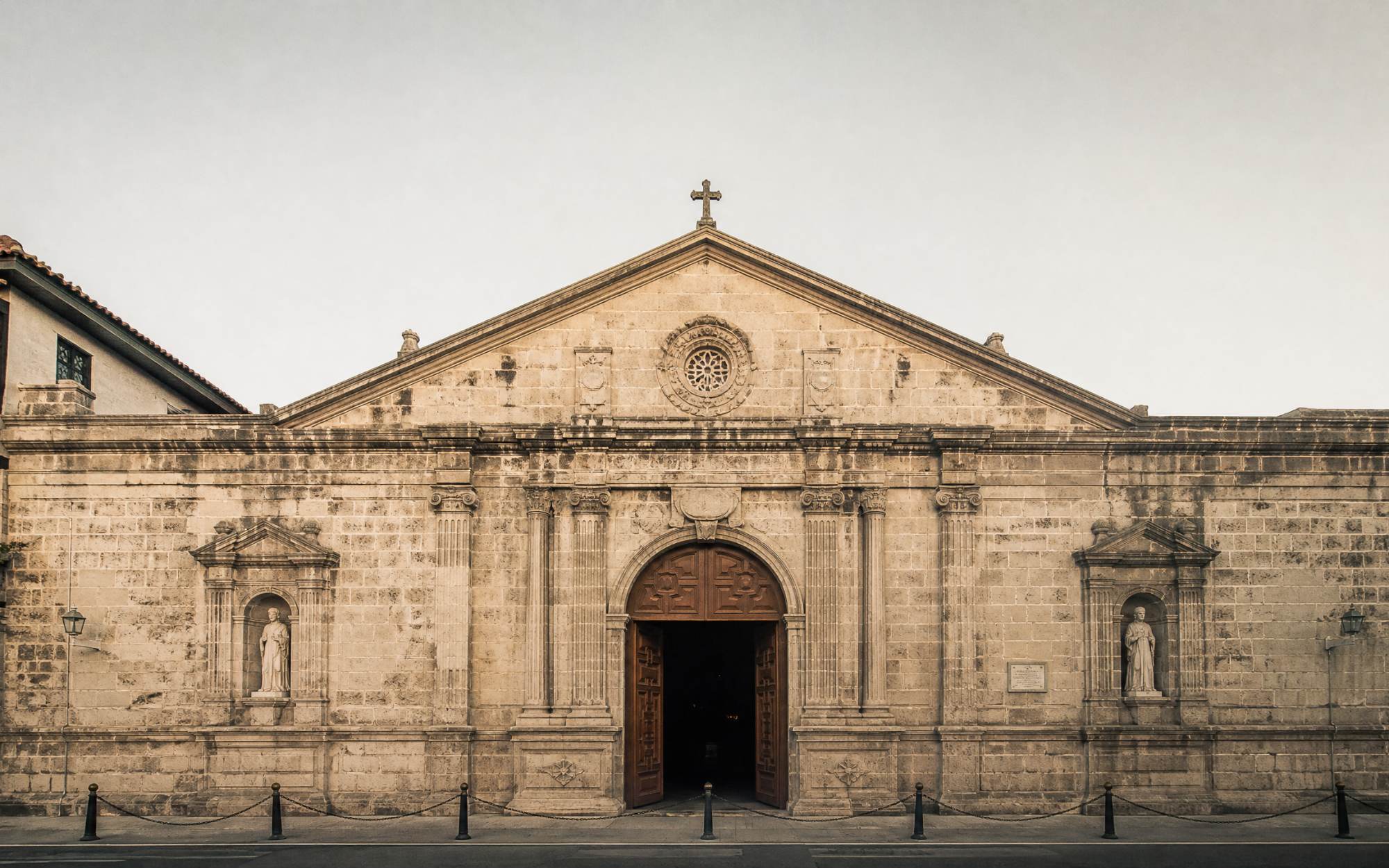 The stone façade of San Agustin Parish in the late afternoon, doors open.
