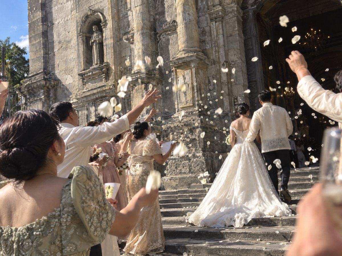 Guests throwing white petals on the church steps as the couple walks out.